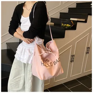 Close-up of pink canvas tote bag with drawstring closure and colorful plaid lining