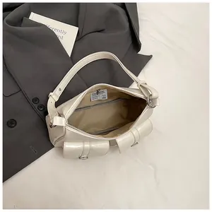 Detail of cream biker-style tote bag with double buckle pockets on grey blazer