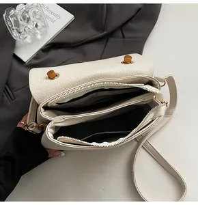Vue détaillée de l'intérieur du sac en cuir litchi avec trois compartiments et ferrures dorées