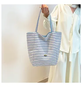Gros plan du sac cabas en toile à rayures bleues avec étiquette de marque en métal chic