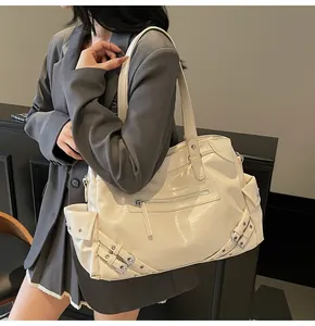 Detail of a creamy white tote bag with glossy leather texture and metal buckle accents