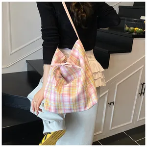 Detailed view of checkered canvas tote bag with pink bow ribbon and pleated opening design