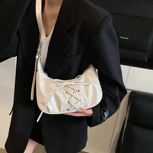 Minimalist white leather crescent shoulder bag with lace-up bow detail on a model