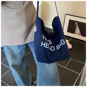 Detail of large navy canvas tote bag with white lettering and classic plaid inner lining