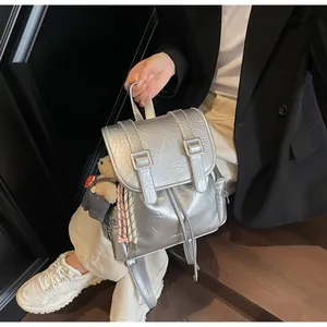 Dettaglio dello zaino metallizzato argento con trama a pieghe e ciondolo orsetto di peluche