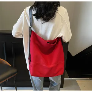 Detailed back view of a large red canvas crossbody bag with adjustable black strap on model