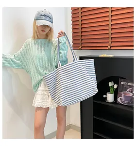 Détail du grand sac cabas en toile rayée porté avec une tenue de mode urbaine chic