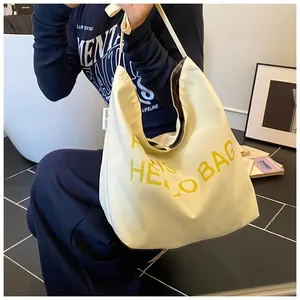 Detail of canvas tote bag showing yellow letter print and spacious hobo style interior