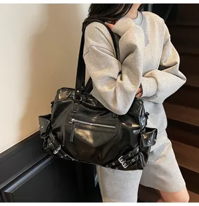 Detailed view of black patent leather tote bag with silver studs and biker style hardware