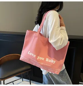 Pink canvas tote bag featuring Love you Baby lettering shown on shoulder by model