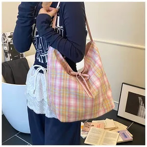 Detailed view of pink plaid canvas tote bag with a decorative bow tied on the shoulder strap