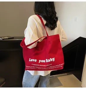 Close-up of red canvas tote bag with white Love you Baby text shown on person