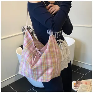 Detail of pink plaid canvas tote bag with bow tie closure shown on person