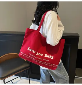Detail of red canvas tote bag showing large white Love You Baby print and sturdy straps