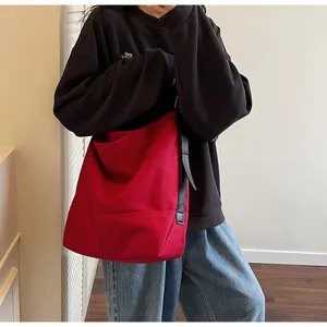 Detailed shot of large red canvas tote bag with black leather strap and exterior pocket