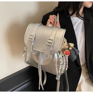 Zaino argento metallizzato con ciondolo a orsetto indossato da modella in nero