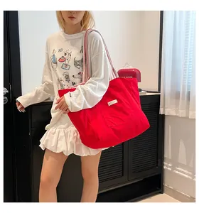 Détail du sac fourre-tout en toile rouge avec poche frontale et bandoulière rayée pour femme
