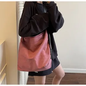 Close-up of a pink oversized faux suede tote bag on a model in minimalist studio setting