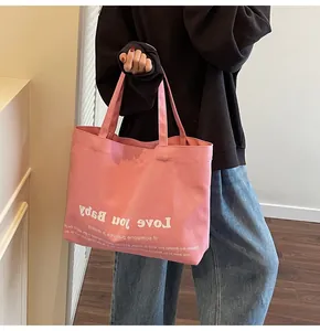 Detail shot of pink canvas tote bag with Love You Baby print on model shoulder