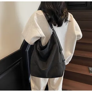 Detail of a large black canvas tote bag with adjustable strap worn on the model's back