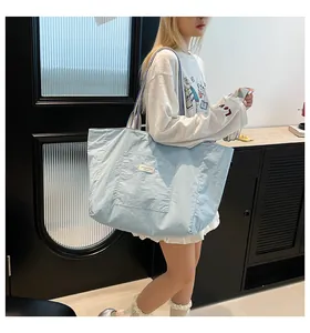 Détail d'un grand sac fourre-tout bleu clair avec bandoulière rayée et poche frontale