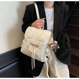 Dettaglio dello zaino tote bianco crema con fibbie e ciondolo a forma di orsetto
