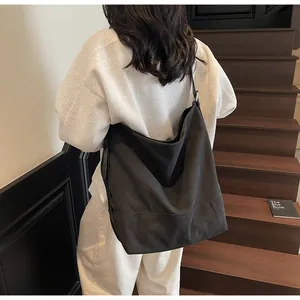 Rear view of model carrying large black minimalist canvas tote bag on dark wooden stairs