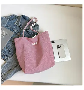 Mise à plat d'un cabas en toile à rayures rouges avec iPad et accessoires du quotidien
