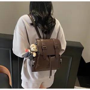 Dettaglio dello zaino in pelle marrone scuro con coulisse e ciondolo a forma di orsetto