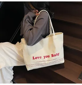 Detail of canvas tote bag featuring Love you Baby red print and stylish typography