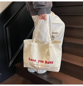Close-up of cream canvas tote bag with Love you Baby red text and motivational quote