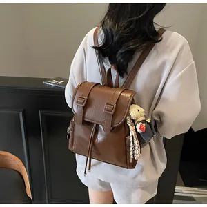 Zaino vintage in ecopelle marrone con ciondolo a orsetto indossato da una modella