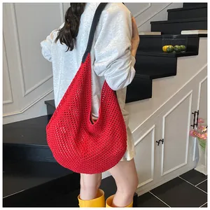 Fashionable red hollow woven shoulder bag with wide black strap shown on a model