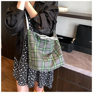 Detail of green plaid canvas tote bag with white ribbon bow and slim shoulder straps