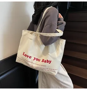 Detailed close-up of heavy-duty cream canvas tote bag with red lettering and shoulder straps