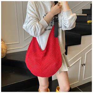 Detail of red hollow crochet tote bag with black leather strap and silver buckle