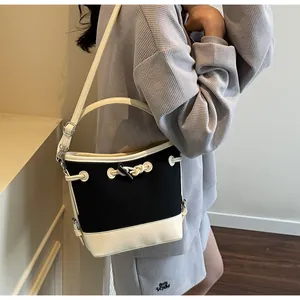 Dettaglio della borsa a secchiello in tela con finiture in pelle e coulisse intrecciata