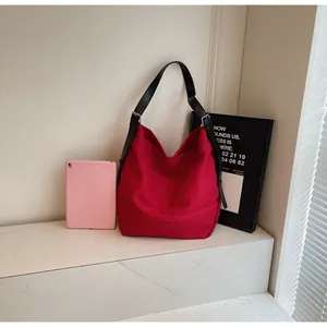 Detail of red canvas tote bag with adjustable black shoulder strap and silver buckle