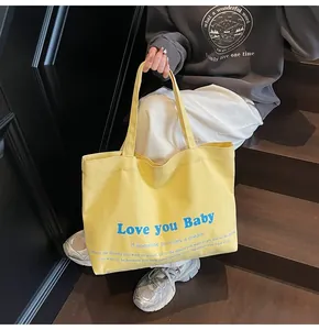 Close-up of bright yellow canvas tote bag with Love you Baby blue print on wooden steps