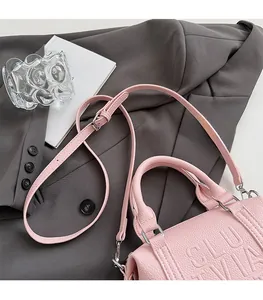 Detail of pink lychee leather Boston bag with embossed logo on a grey blazer