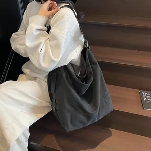 Minimalist black canvas tote bag with adjustable strap shown on wooden stairs