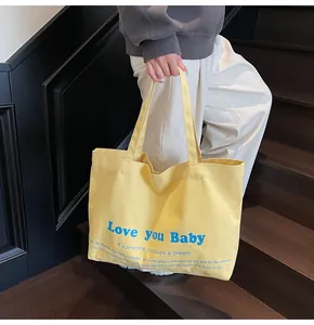 Close-up of yellow canvas tote bag with Love you Baby print on wooden stairs