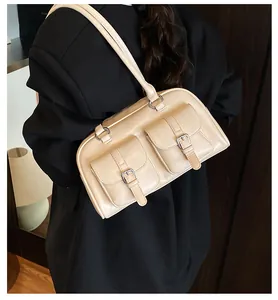 Dettaglio di una borsa beige in ecopelle con tasche e fibbie su una giacca blazer nera