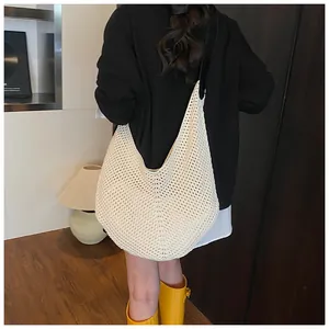Detail of a large cream knit crescent bag showing mesh texture on a model's shoulder