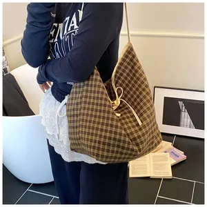 Detail of large brown plaid canvas tote bag with adjustable drawstring and cream straps