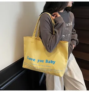 Detail of yellow canvas tote bag with Love You Baby print and durable shoulder strap