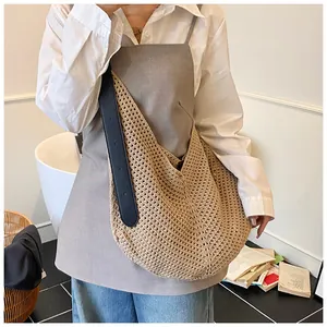 Close-up of beige woven crochet tote bag featuring adjustable black leather shoulder strap