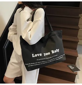 Detail shot of the large capacity black canvas tote bag with white art font on stairs