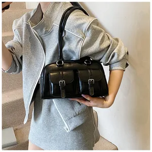 Dettaglio borsa a spalla in pelle nera lucida con due tasche a fibbia e finiture argento