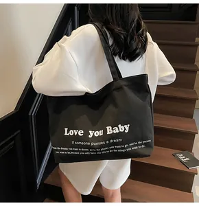 Close-up of black canvas tote bag with white quote print on indoor wooden stairs
